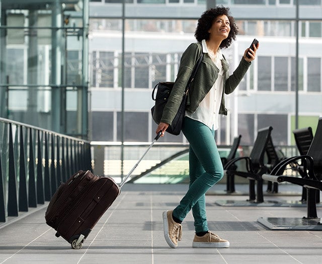 Happy woman traveling with her Leaders checking account